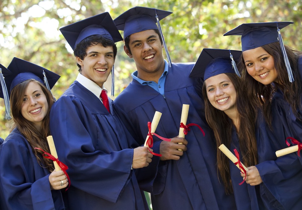 Graduating students smiling and laughing with diplomas